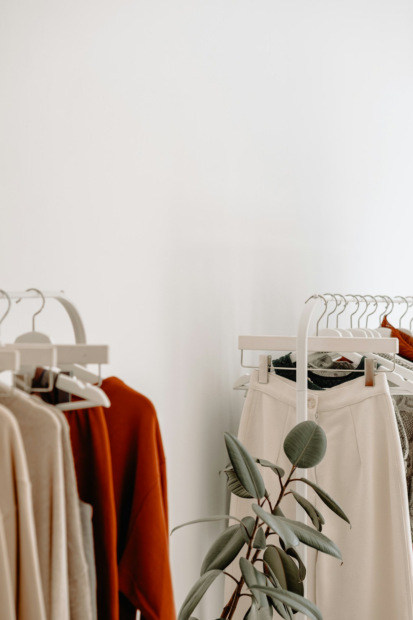 Neutral-toned clothing on racks in a bright boutique