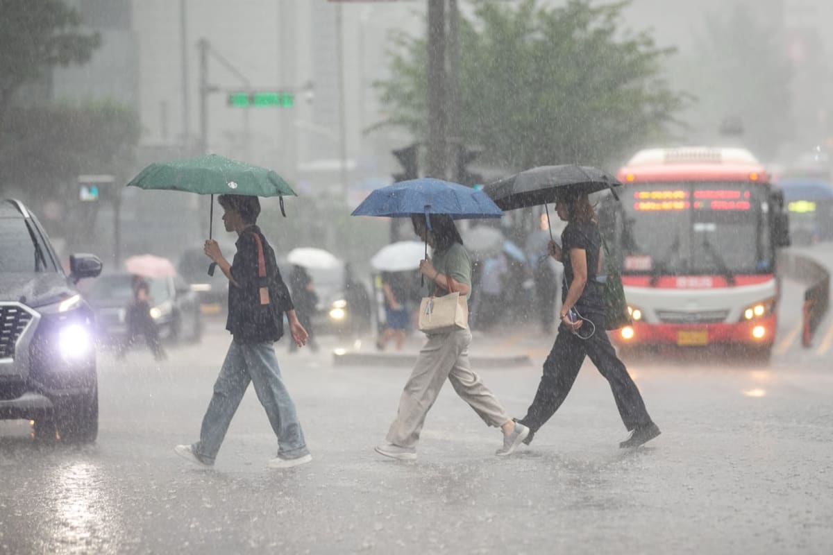 Pedestrians crossing a Seoul street in heavy rain with colorful umbrellas